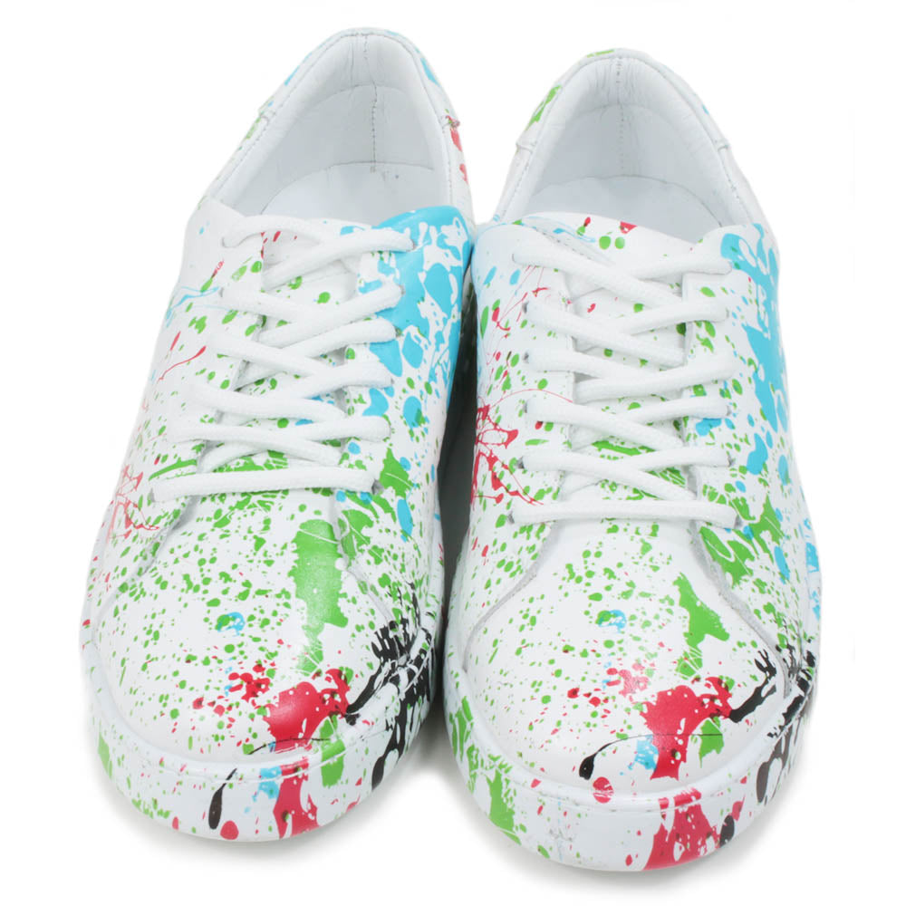 Leather white trainers with paint splash decoration. Six hole lace ups. Front view.