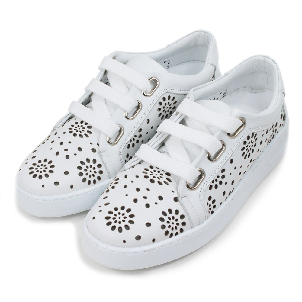 White training shoes with white rubber soles. Punched holes patterns over the entire shoes. Three holes while flat laces. Angled view.