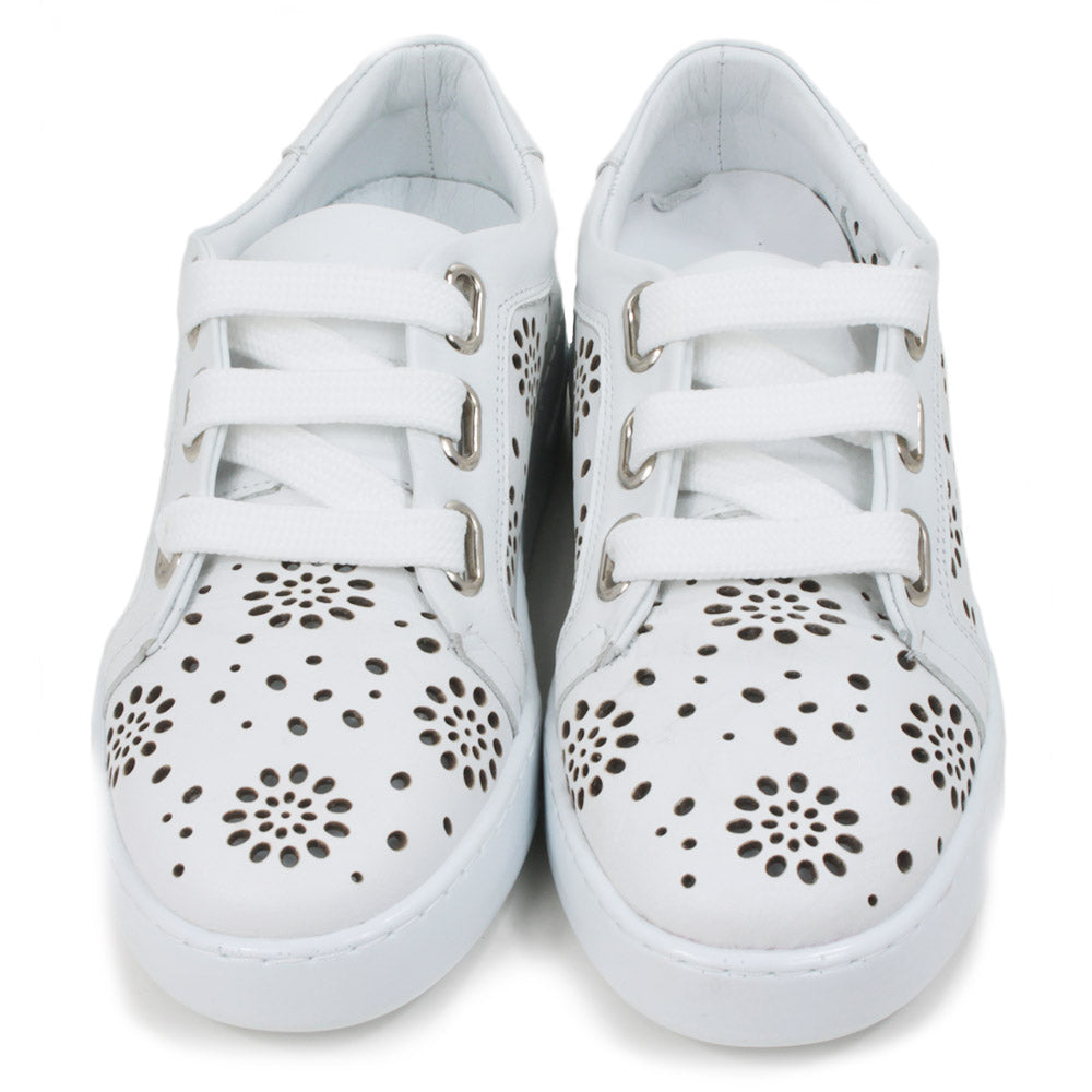 White training shoes with white rubber soles. Punched holes patterns over the entire shoes. Three holes while flat laces. Front view.