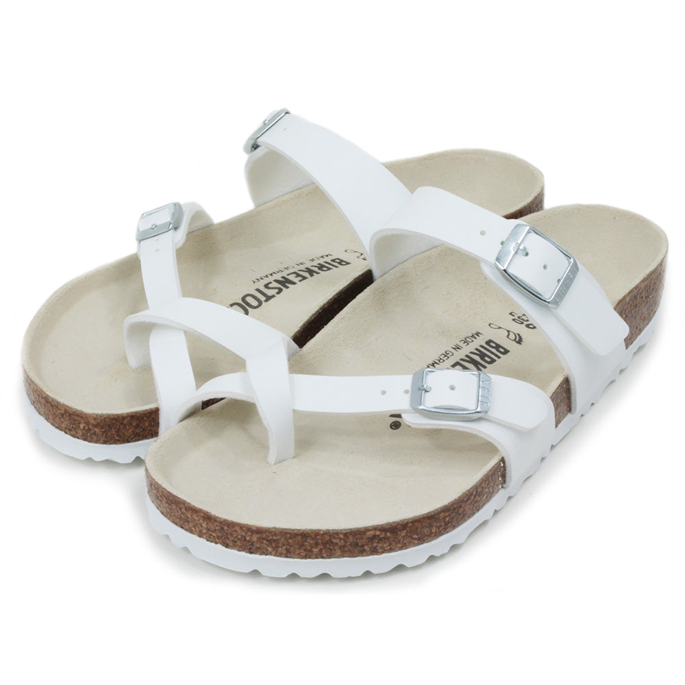 Birkenstock Mayari three strap white sandals. Silver buckles for adjustment. Strap to fit between toes. Open backs. Cork insoles with white soles. Angled view.