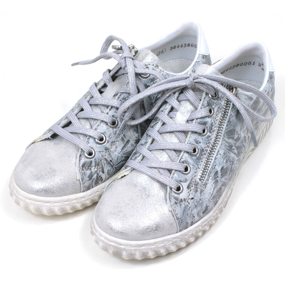 Rieker trainers in silver floral pattern. Lace up adjustment and zip fitting. Angled view.