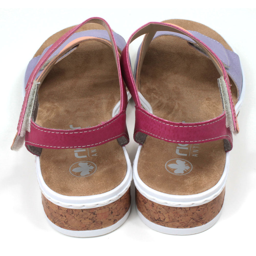 Rieker sandals with sand coloured footbed. Violet, orange and rose pink straps which adjust and fit with Velcro. Soles have white edging. Back view.