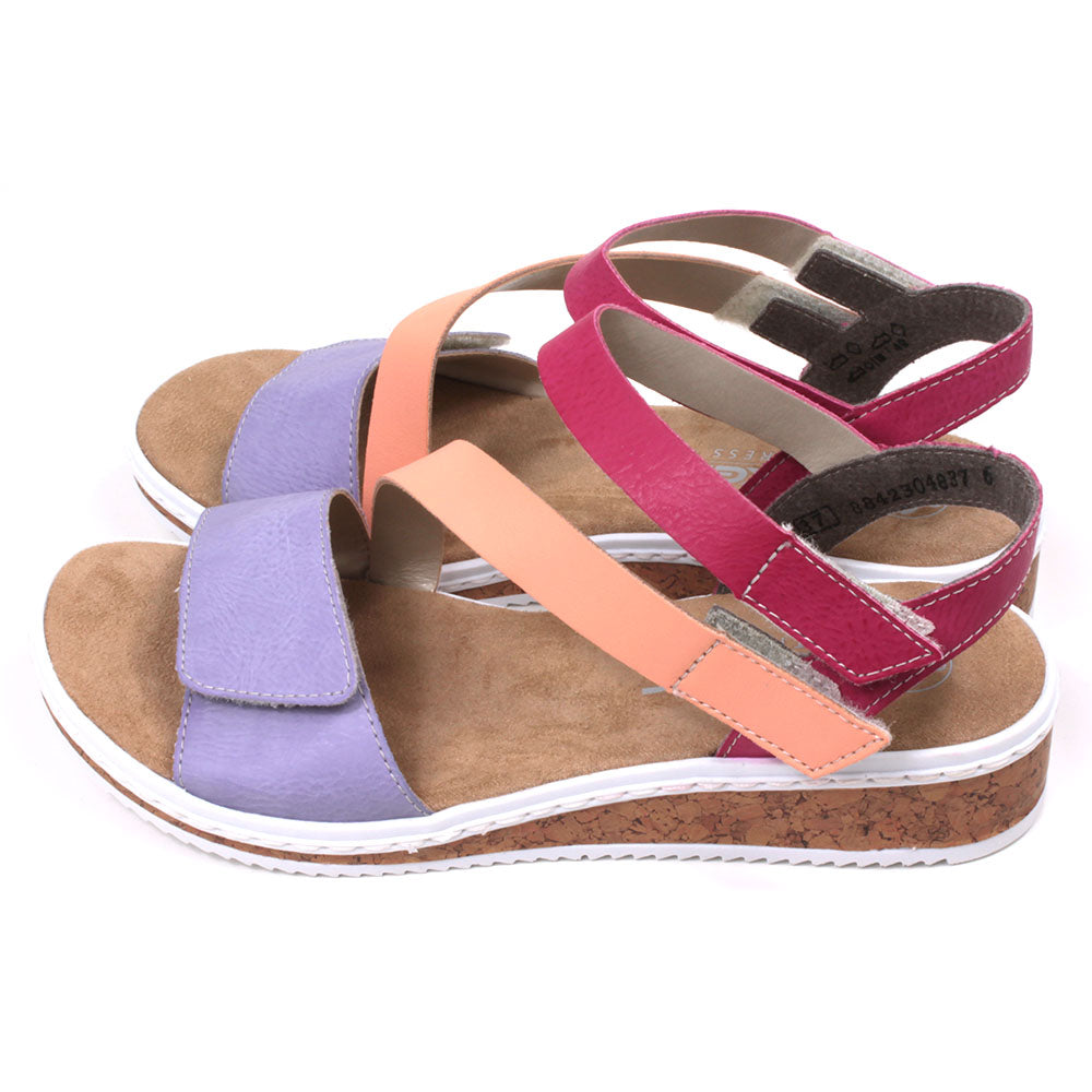 Rieker sandals with sand coloured footbed. Violet, orange and rose pink straps which adjust and fit with Velcro. Soles have white edging. Side view.