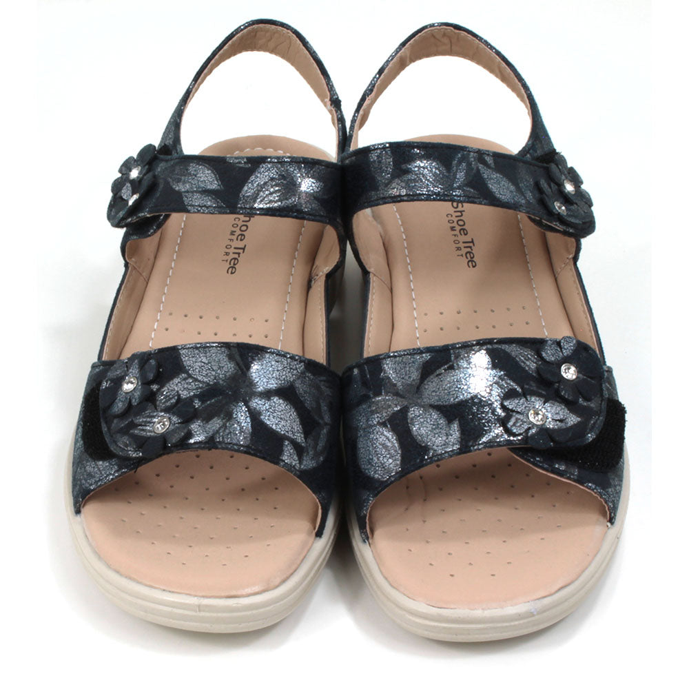 Navy sandals with floral pattern on fabric. Double straps across the feet fastened with Velcro. Straps around the ankles. Light tan, padded insoles. Low heels. Front view.
