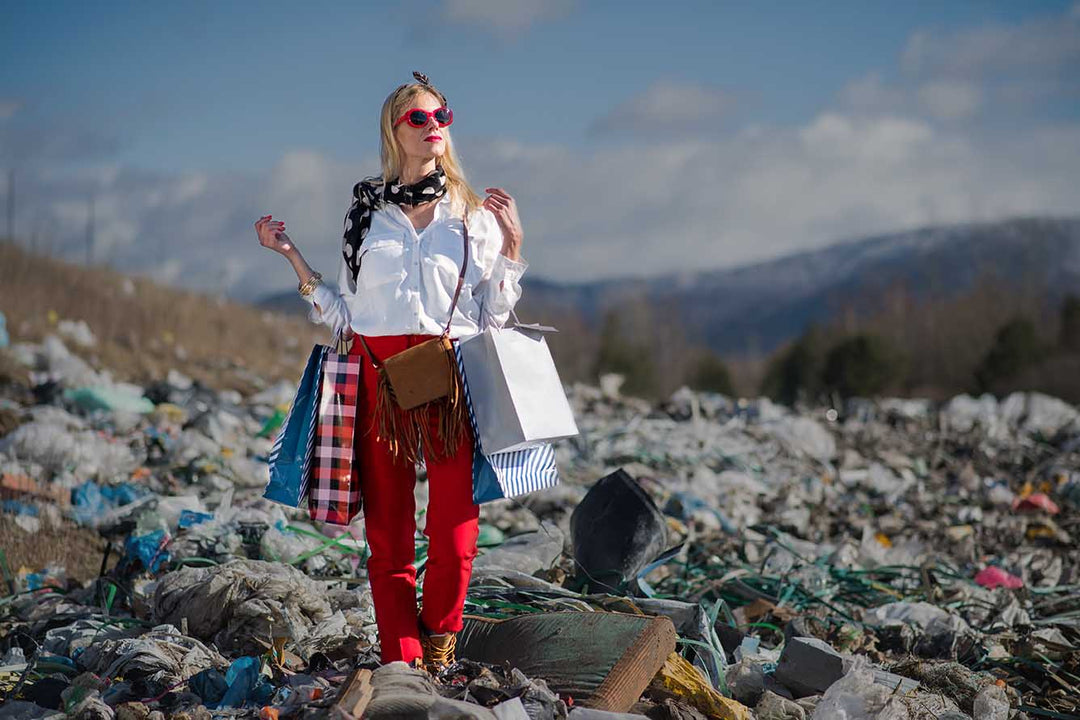 Young woman holding carrier bags amongst piles of trash