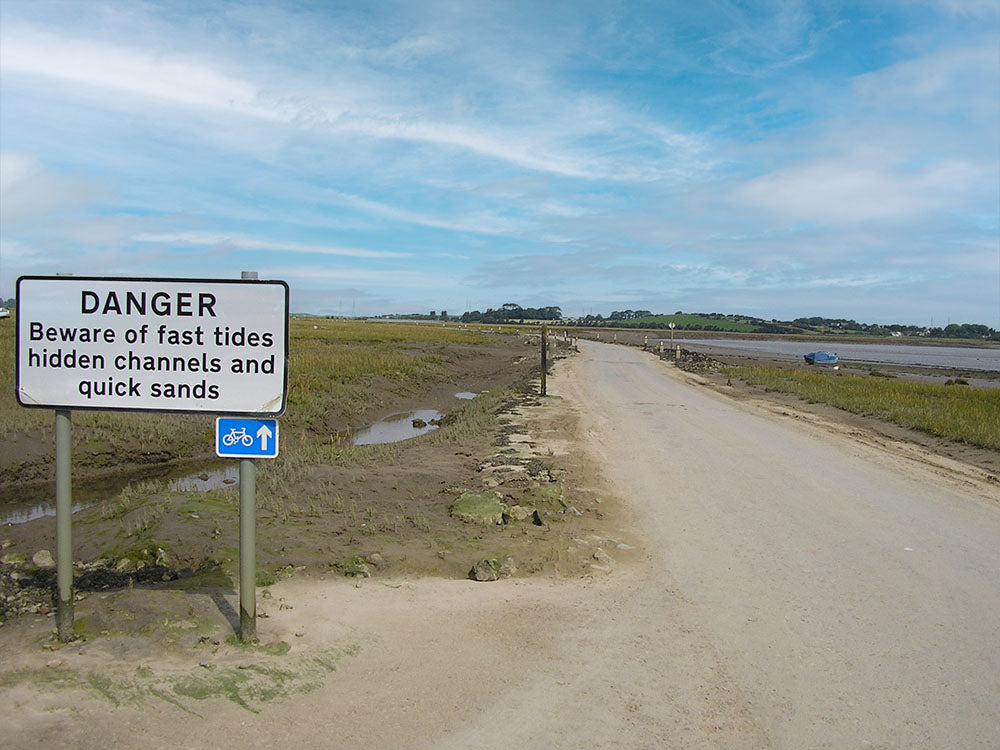 Road across the sands from Sunderland Point. Road sign warning of fast tides and quick sands
