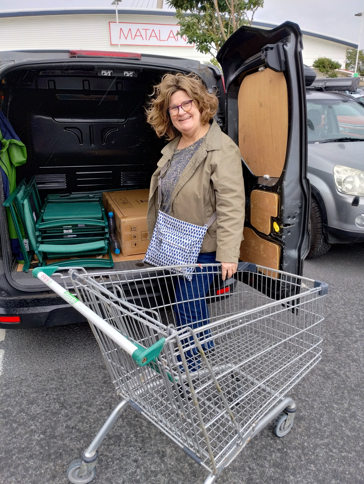 Caroline with a supermarket trolley loading folding chairs into our van.