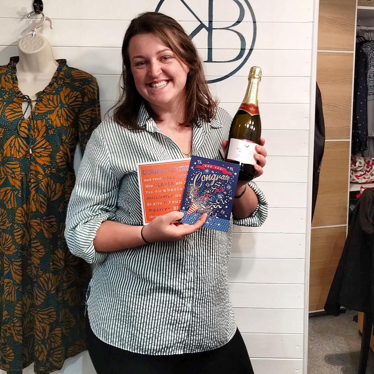 Ella holding a bottle of fizz and some cards.