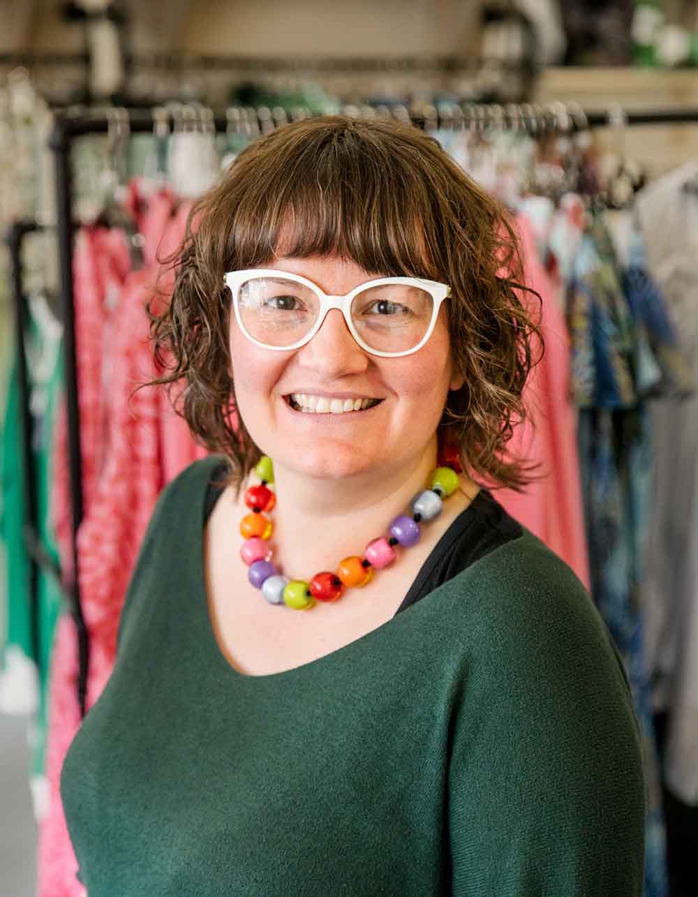 Trueman wearing a colourful bead necklace and white glasses smiling at the camera.