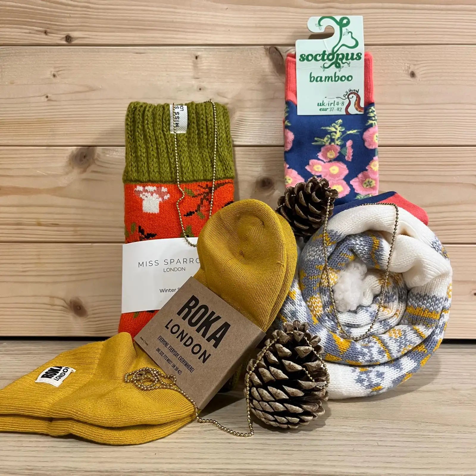 Socks against a pine board background and a pine cone.