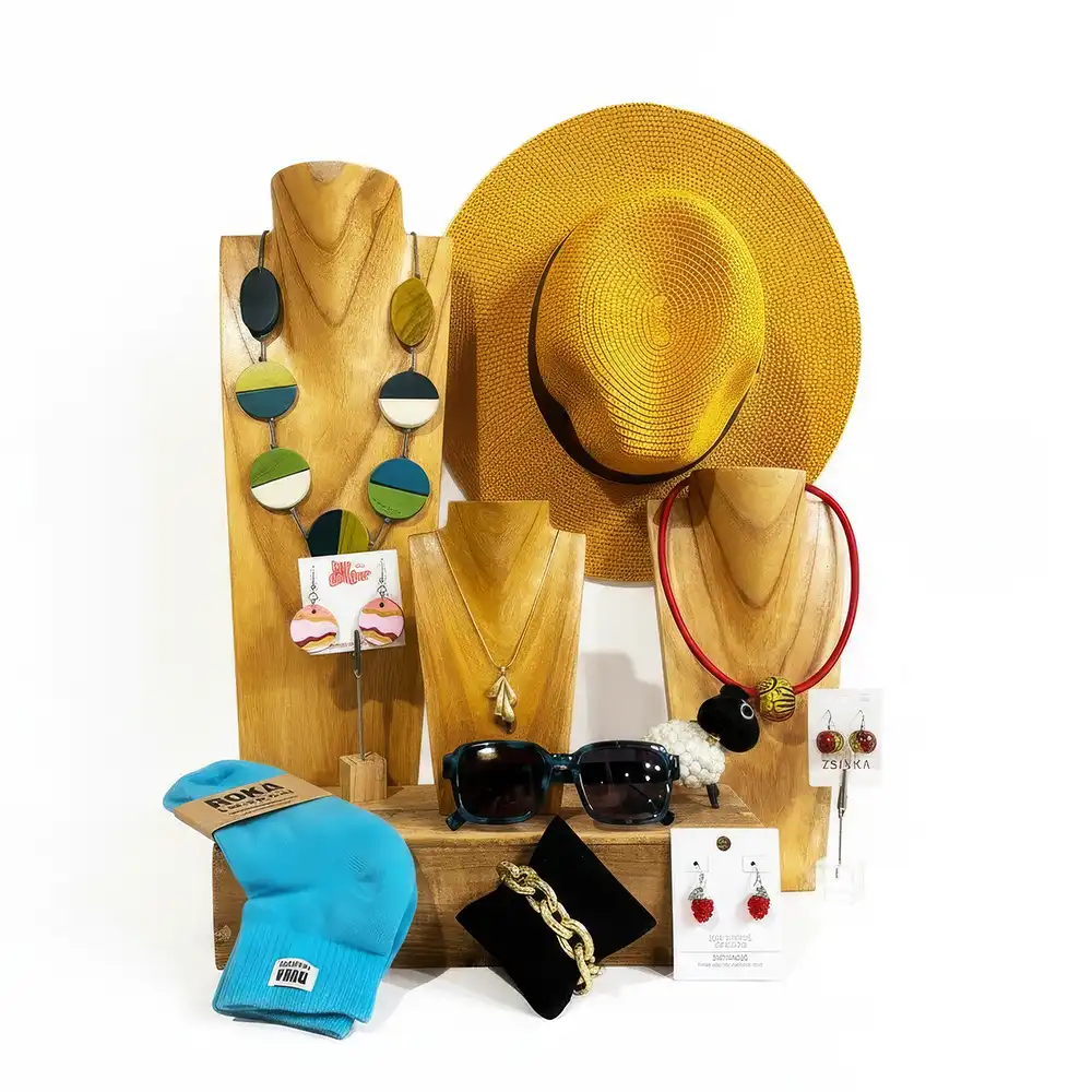Collection of accessories including a yellow hat, sunglasses, and jewelry on a wooden stand with a white background.