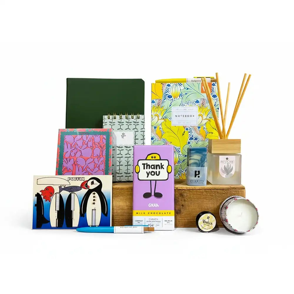 Collection of stationery items including notebooks, candles, and a chocolate bar on a white background