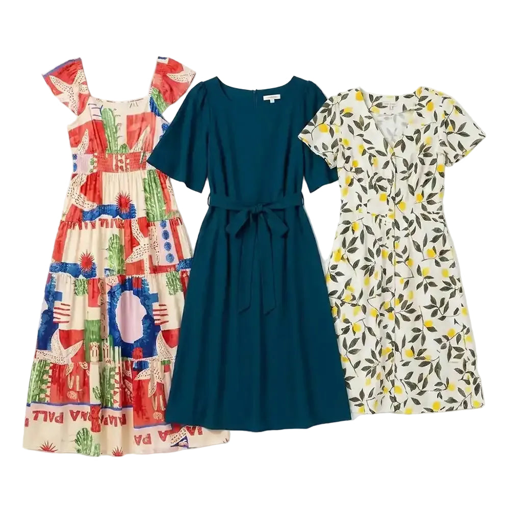 Three women's short-sleeve dresses laid flat on a white background: a multicolor patchwork-style dress on the left, a solid dark teal dress in the center, and a cream dress with a yellow and green leaf print on the right.