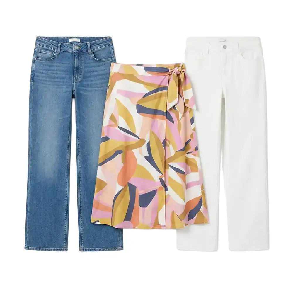 Three pairs of children's pants laid flat on a white background: blue denim jeans, white pants, and a wrap-style skirt with an abstract floral pattern in pink, yellow, orange, and navy.