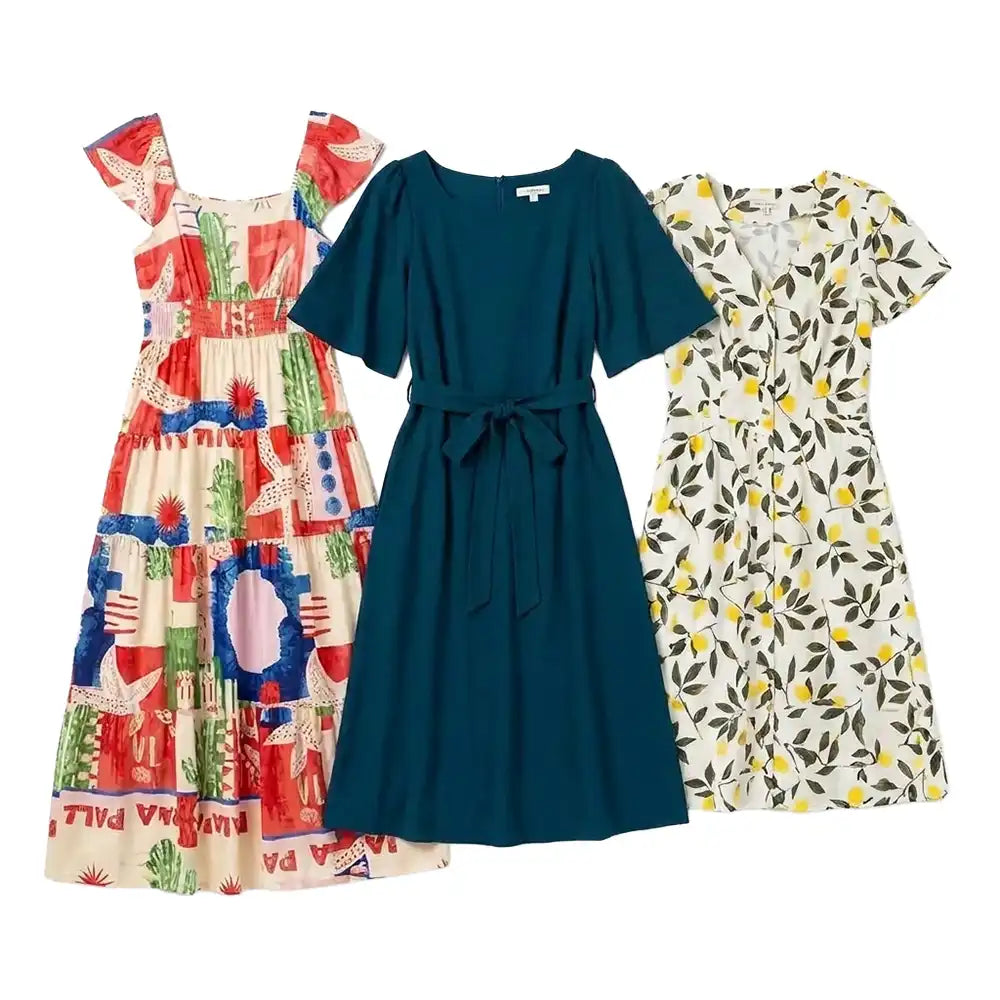 Three women's short-sleeve dresses laid flat on a white background: a tiered cream dress with a colorful red, blue, and green patchwork-style print on the left; a solid dark teal belted dress in the center; and a cream dress with a yellow and green leaf print on the right.