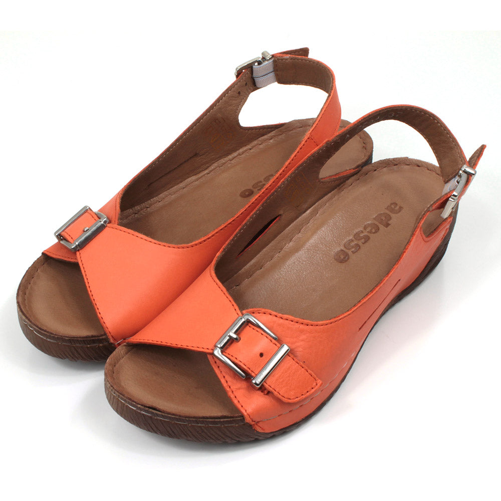 Adesso tangerine orange sandals with buckled strap over the toes and an adjustable strap around the heels. Low heeled. Angled view.