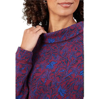 Close-up of a person wearing a long-sleeve knit top with a red and blue floral pattern, holding the collar with one hand.