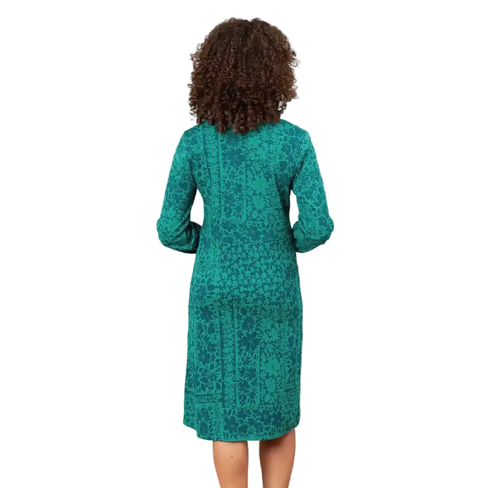 A woman viewed from the back wearing a teal green long-sleeve dress with an intricate dark pattern, set against a solid white background.