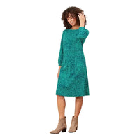 A woman modeling a teal green long-sleeve midi dress with a tonal floral pattern, standing against a solid white background.