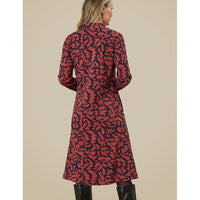 Woman wearing a red and black patterned dress against a beige background