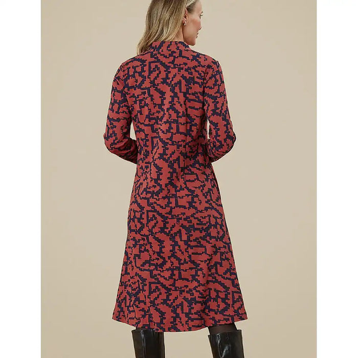 Woman wearing a red and black patterned dress against a beige background