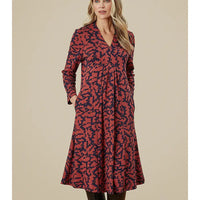 Woman wearing a red and black patterned dress on a beige background