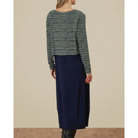 Person wearing a striped long-sleeve top and navy skirt on a beige background