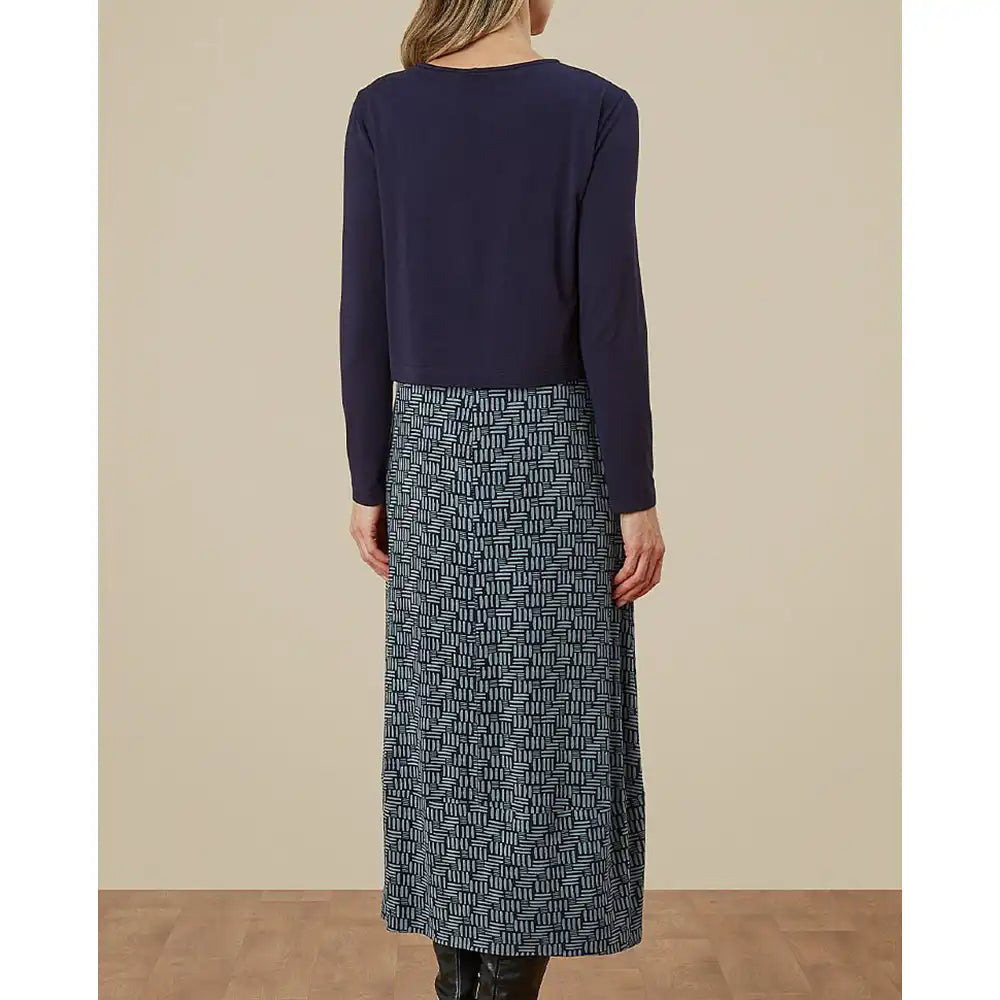 Person wearing a navy long-sleeve top and patterned skirt on a beige background