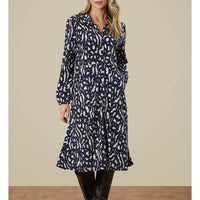 Woman wearing a navy and white patterned dress against a beige background