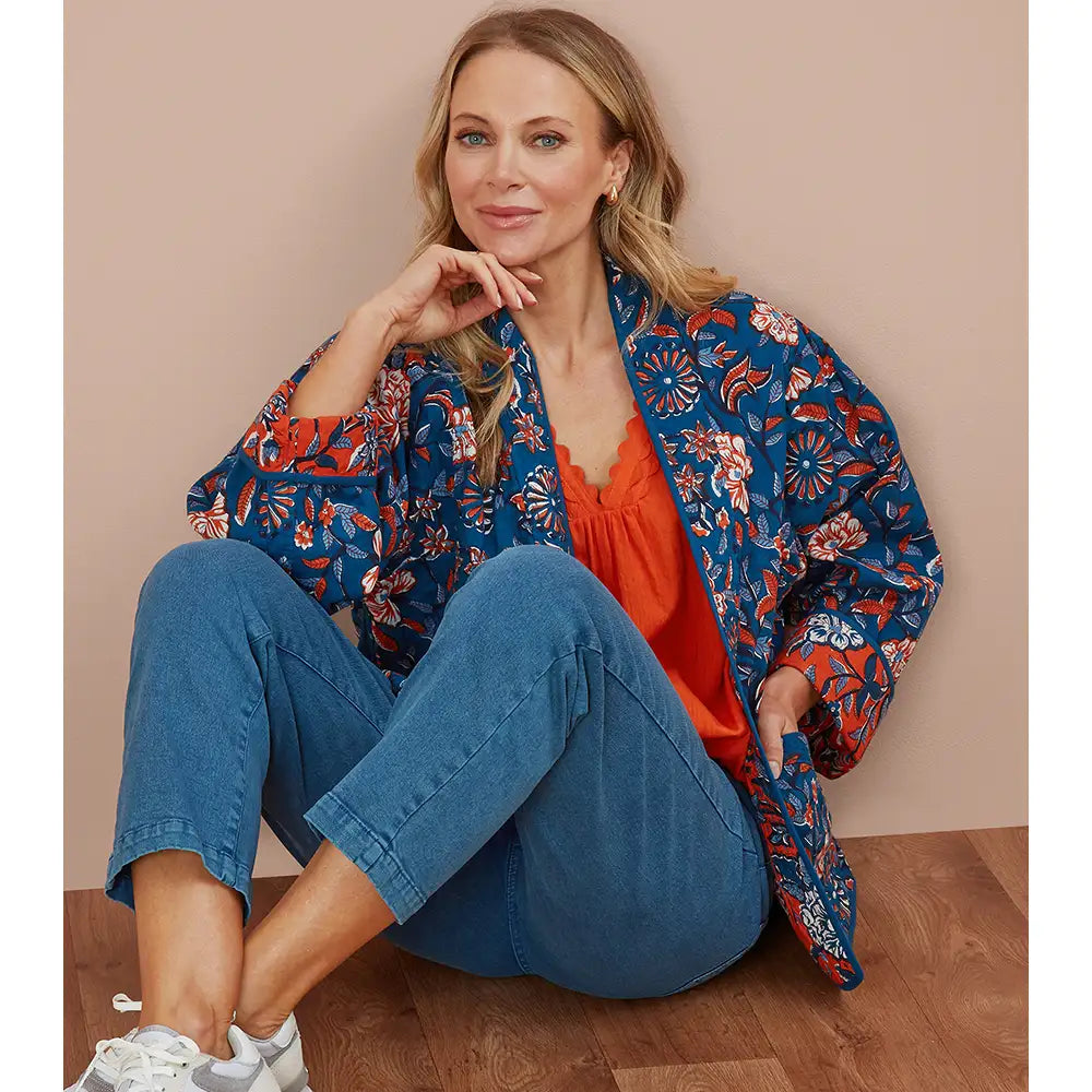 Woman wearing an blue floral kimono on a beige background. 