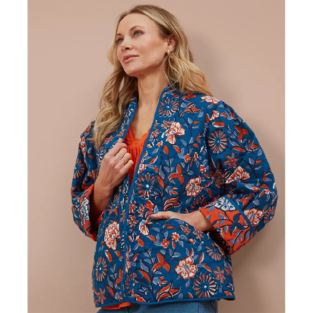 Woman wearing an blue floral kimono on a beige background. 