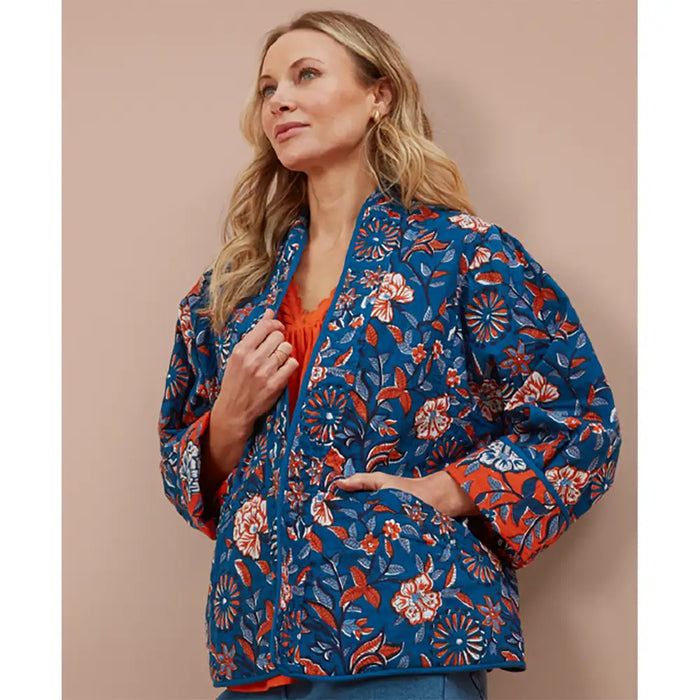 Woman wearing an blue floral kimono on a beige background. 