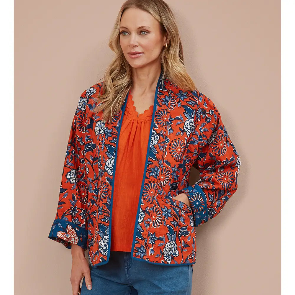 Woman wearing an orange floral kimono on a beige background. 