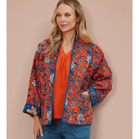 Woman wearing an orange floral kimono on a beige background. 