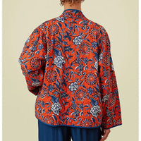 Woman wearing an orange floral kimono on a beige background. 