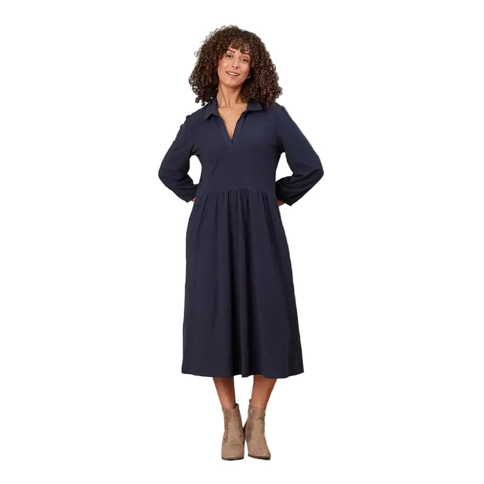 A woman modeling a long-sleeve navy midi dress with a collared neckline and gathered waist, standing in a white environment.