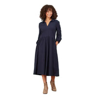 A woman modeling a dark navy blue long-sleeve midi dress with a V-neckline and side pockets, standing against a solid white background.