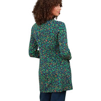 A woman shown from the back wearing a long-sleeve tunic-style top with an all-over abstract paisley-like print in green, teal, orange, and dark navy, paired with dark blue jeans against a plain white background.