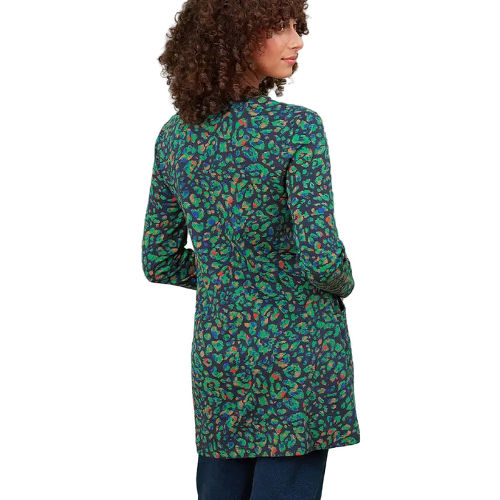 A woman shown from the back wearing a long-sleeve tunic-style top with an all-over abstract paisley-like print in green, teal, orange, and dark navy, paired with dark blue jeans against a plain white background.