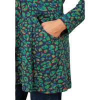 A close-up of a person wearing a long-sleeve wrap-style top with a colorful abstract print on a dark navy background. The print features green, blue, orange, and red shapes.