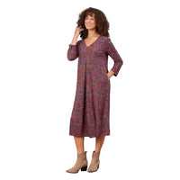 A woman modeling a long-sleeve V-neck midi dress with a dense multicolor floral print, standing against a white background.