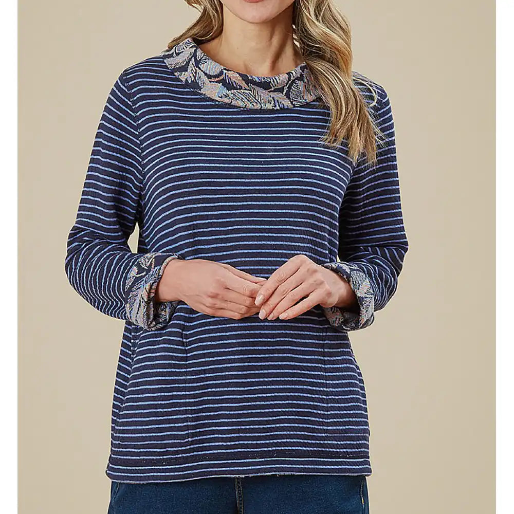 Woman wearing a blue striped shirt with patterned cuffs on a beige background