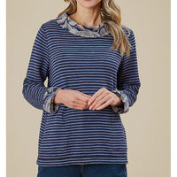 Woman wearing a blue striped shirt with patterned cuffs on a beige background