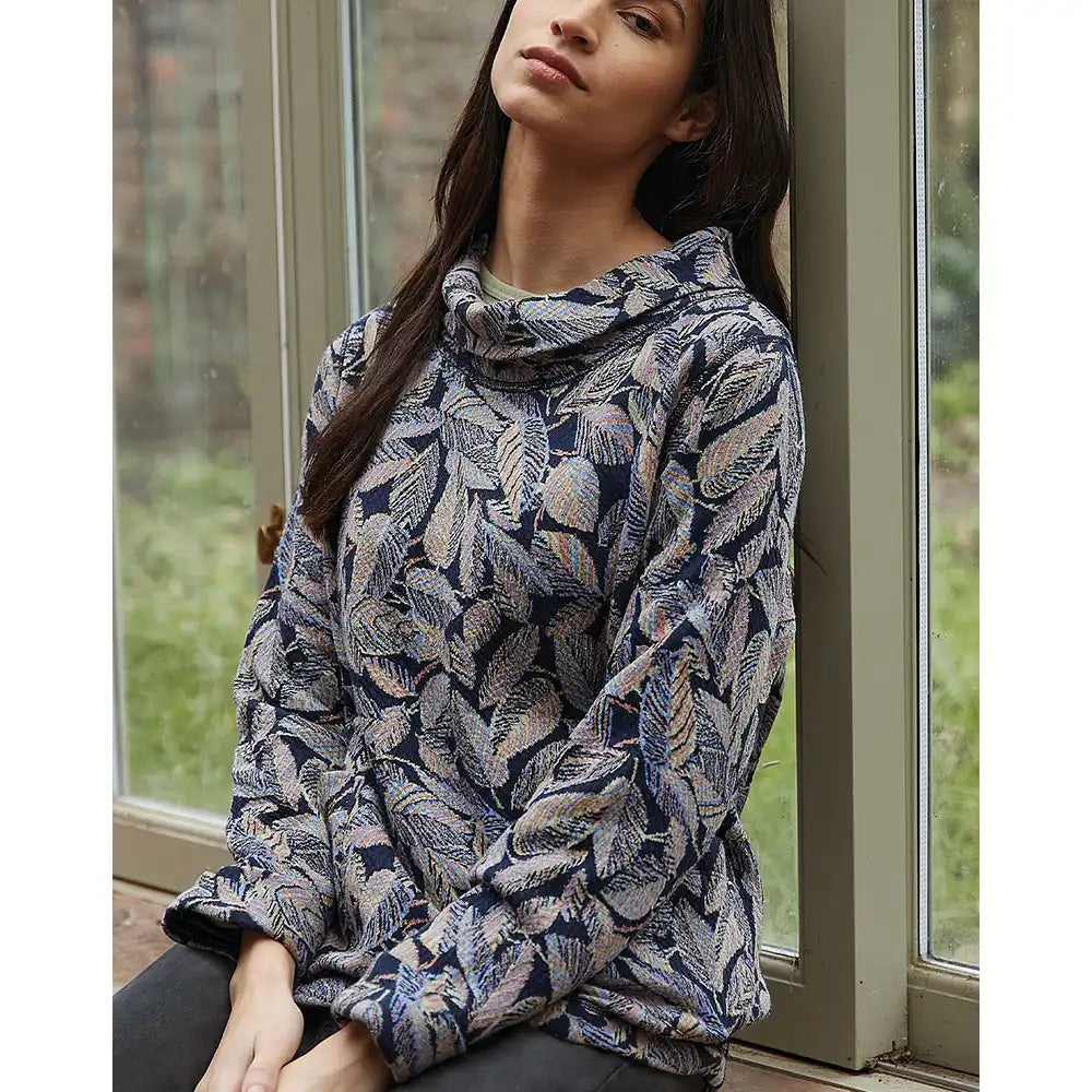 Woman wearing a patterned sweater sitting by a window