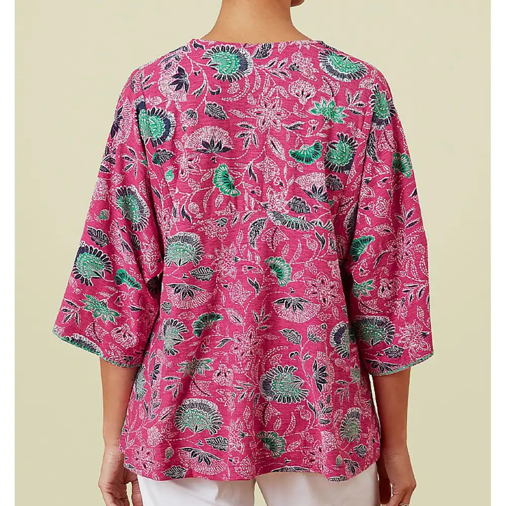 Pink floral patterned top worn by a person on a beige background