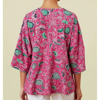 Pink floral patterned top worn by a person on a beige background
