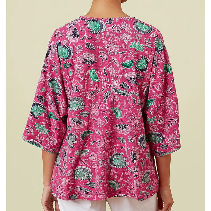 Pink floral patterned top worn by a person on a beige background