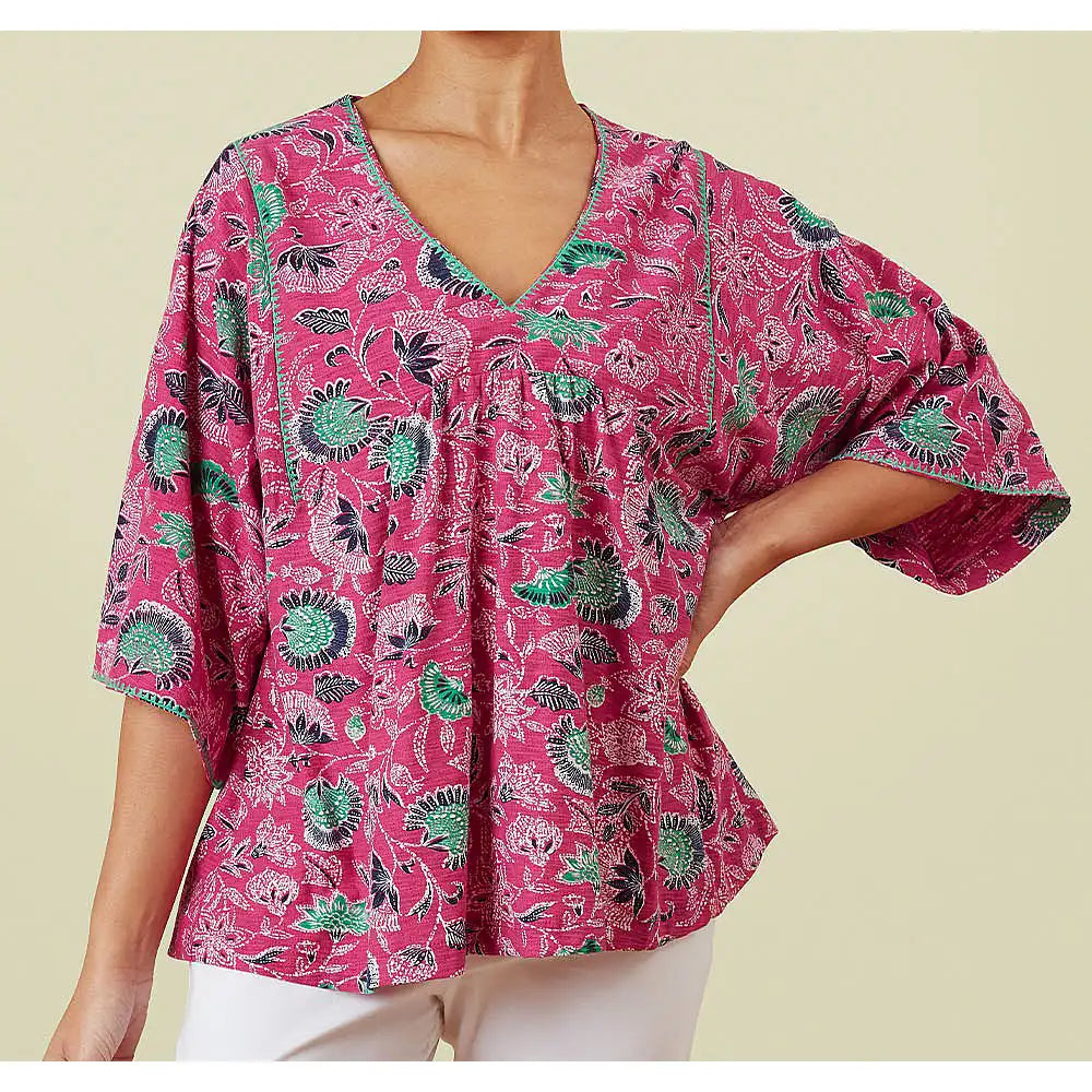 Front of a pink v neck top with wide elbow length sleeves with green, navy blue and white flowers.