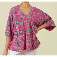 Front of a pink v neck top with wide elbow length sleeves with green, navy blue and white flowers.