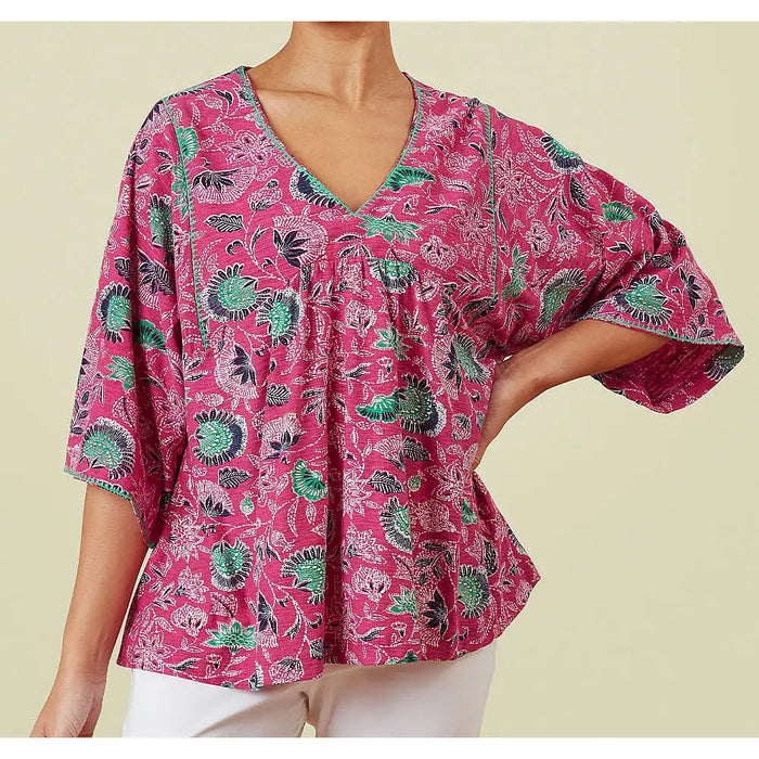 Front of a pink v neck top with wide elbow length sleeves with green, navy blue and white flowers.